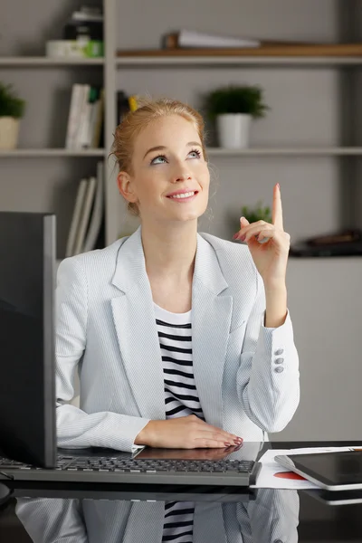 Young businesswoman pointing upwards.