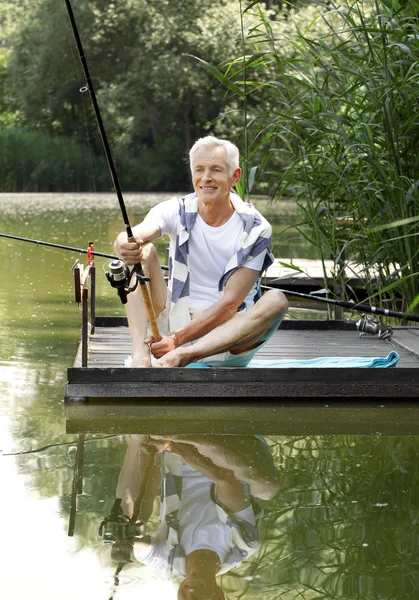 Senior man  at the lakeside and fishing.