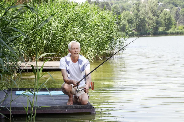 Senior man  at the lakeside and fishing.