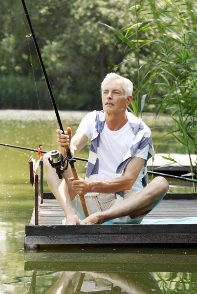 Senior man  at the lakeside and fishing.
