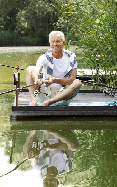 Senior man sitting at pier and fishing.