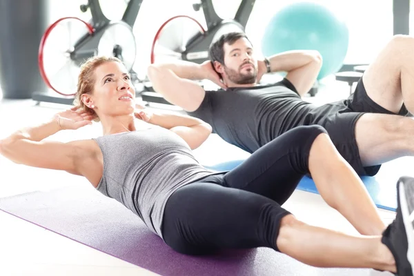 Man and woman training together at the gym.