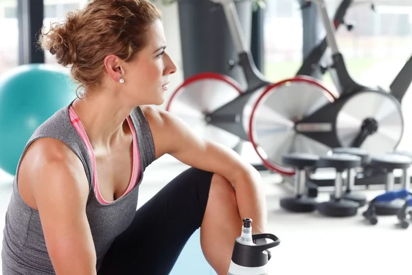 Sporty woman sitting at gym after workout
