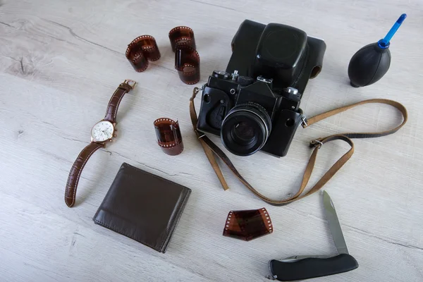 Work space for photographer, designer or hipster style. Have a film camera, film, watch, wallet, knife on wooden table.