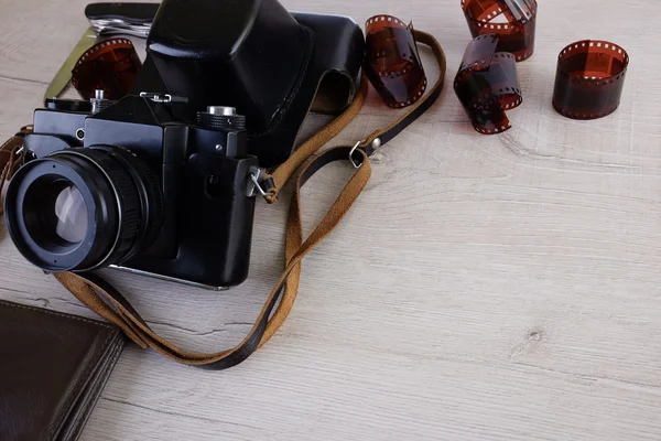 Work space for photographer, designer or hipster style. Have a film camera, film, watch, wallet, knife on wooden table.