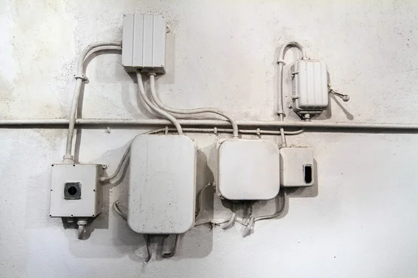 Old white electrical network of cables on a wall.