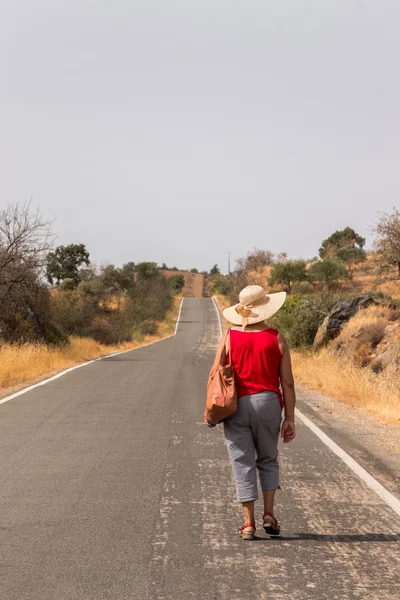 Elder woman with straw hat walks