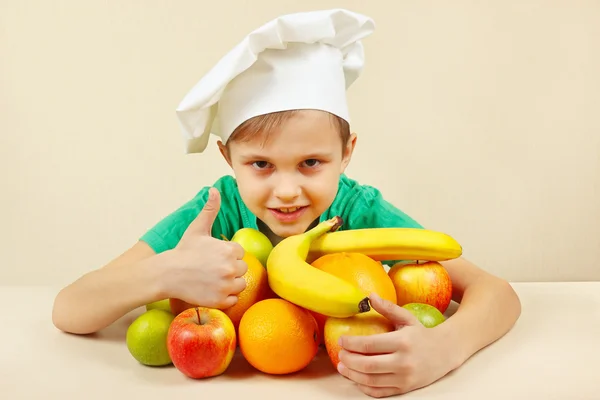 Little boy in chefs hat with fruits at table
