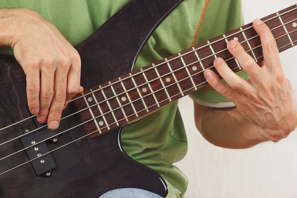 Hands of a rock musician playing the electric bass guitar