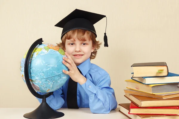 Little boy in academic hat with geographical globe