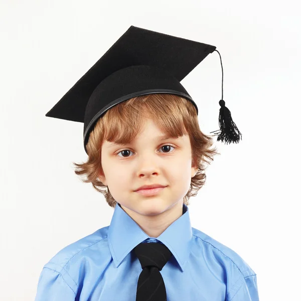 Little serious boy in academic hat on white background