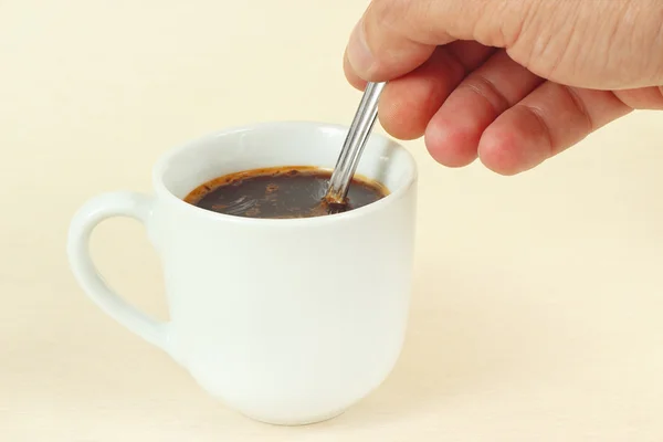 Hand mixing with spoon of aromatic coffee in the cup