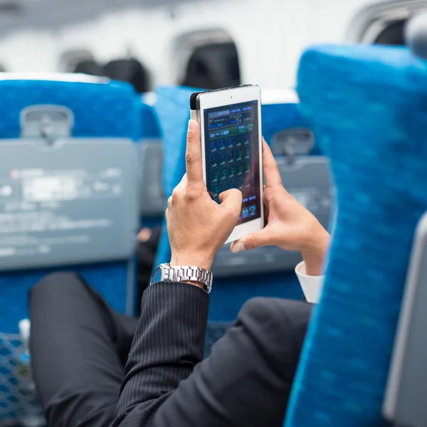 Businessman using tablet phone on airplane.