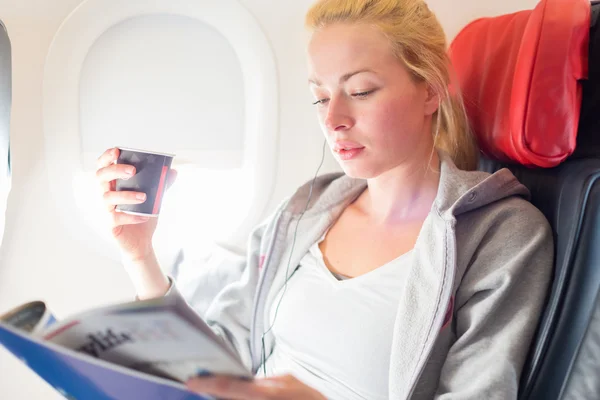 Woman reading magazine on airplane.