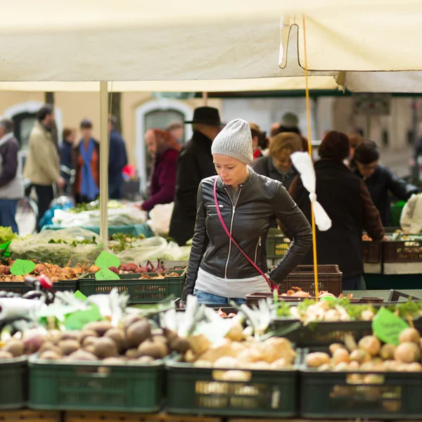 Woman buying vegetable at local food market.