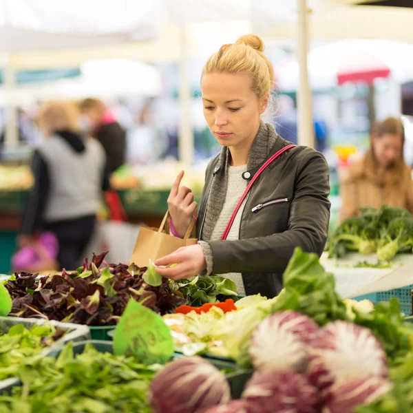 Woman buying vegetable at local food market.