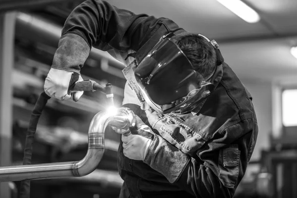 Industrial worker welding in metal factory.