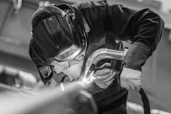 Industrial worker welding in metal factory.