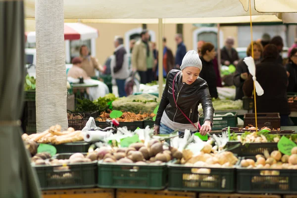 Woman buying vegetable at local food market.