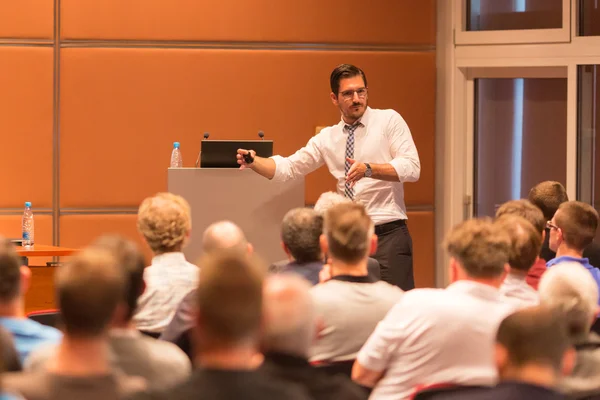 Business speaker giving a talk in conference hall.