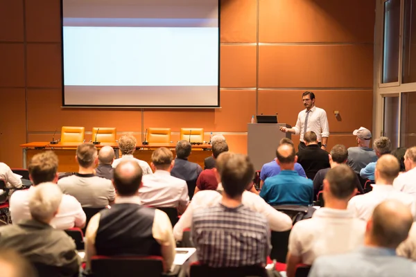 Business speaker giving a talk in conference hall.