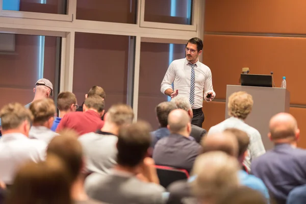 Business speaker giving a talk in conference hall.