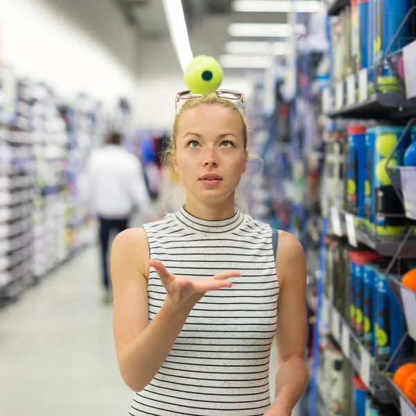 Woman shopping tennis balls in sportswear store.