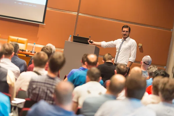 Business speaker giving a talk in conference hall.