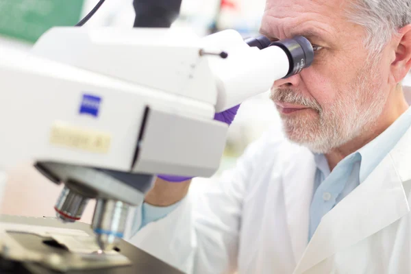 Senior scientist microscoping in lab.