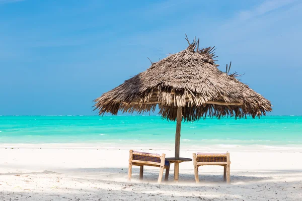 Two deck chairs and umbrella on tropical beach.