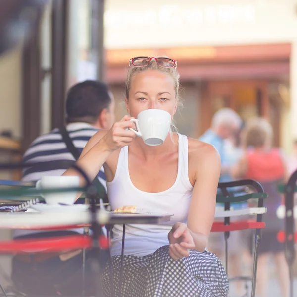 Woman drinking coffee outdoor on street.