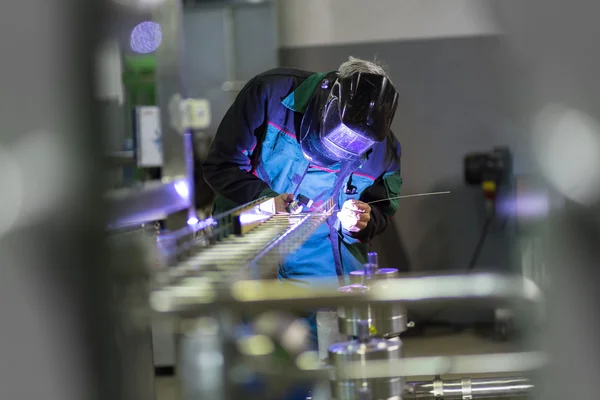 Industrial worker welding in metal factory.