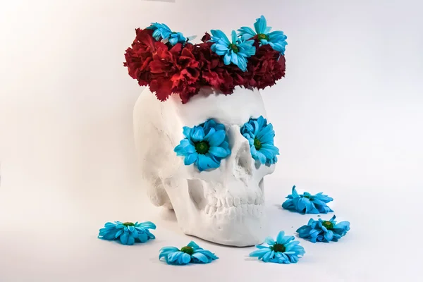 Skull with a wreath of roses and blue flowers