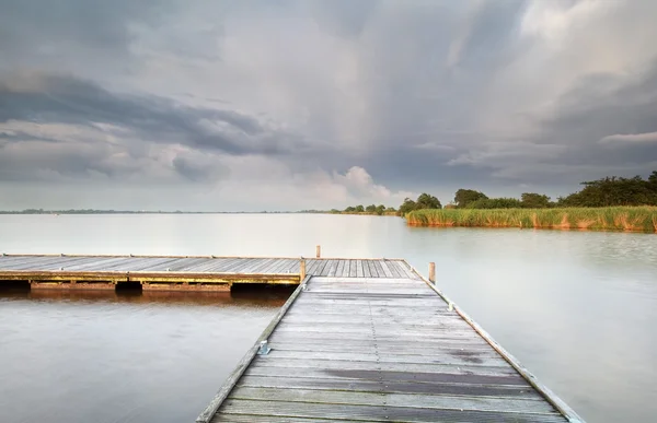 Wooden pier on big lake and clouded sky