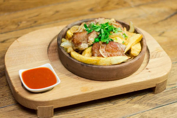 Grilled pork with roasted potato and sauce on clay pan
