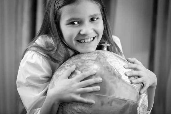 Black and white portrait of smiling girl posing with Earth globe