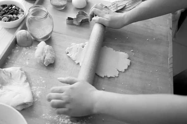 Black and white photo of woman using rolling pin while cooking