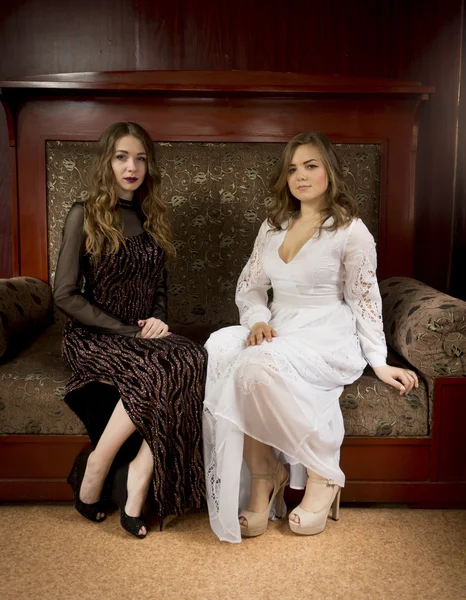 Two beautiful women sitting on vintage sofa at old room