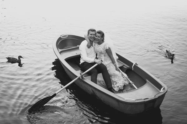 Black and white photo of bride and groom posing on old rowing bo