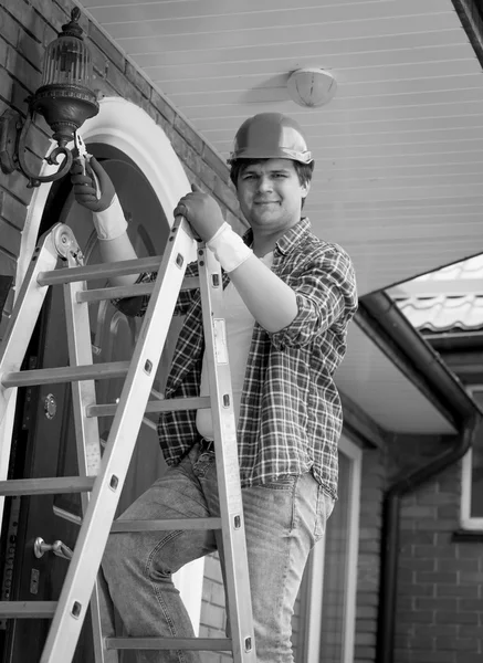 Black and white portrait of smiling electrician posing on top of