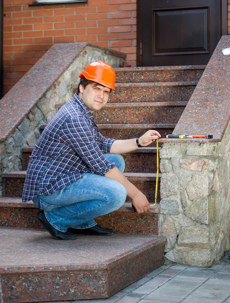 Young contractor worker measuring staircase with measuring tape