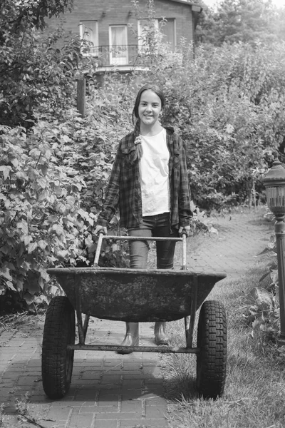 Black and white image of cute young teen girl posing with wheelb