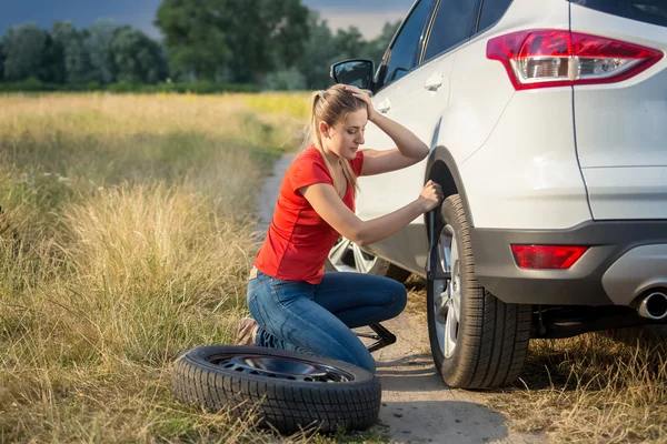 Sad woman got confused about changing flat tire in the field