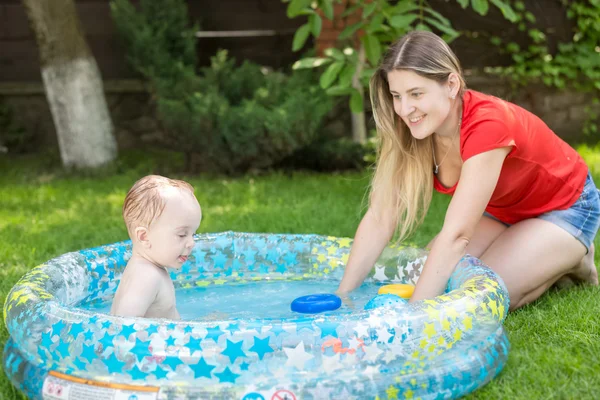 Mother and her baby boy playing in swimming pool at hot summer d