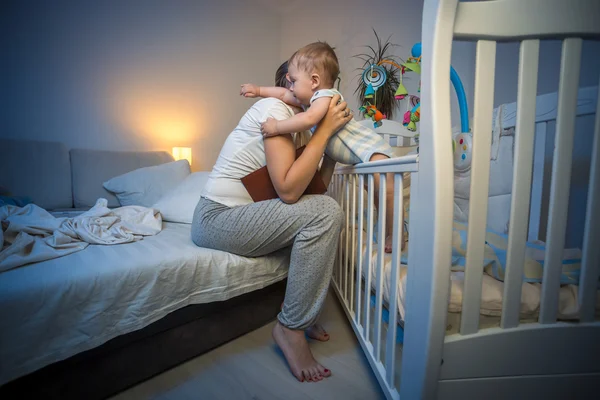 Cute baby got scared at night at hugging young caring mother