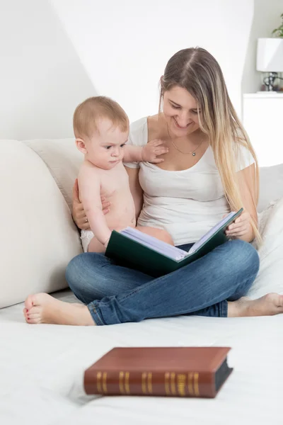 Beautiful mother showing images in old book to her 9 months old