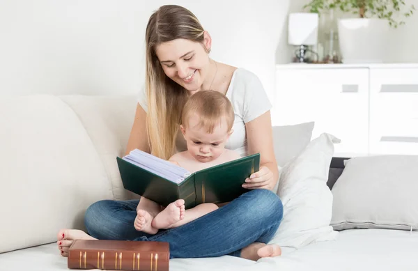 Smiling mother reading story to her 9 months old baby boy