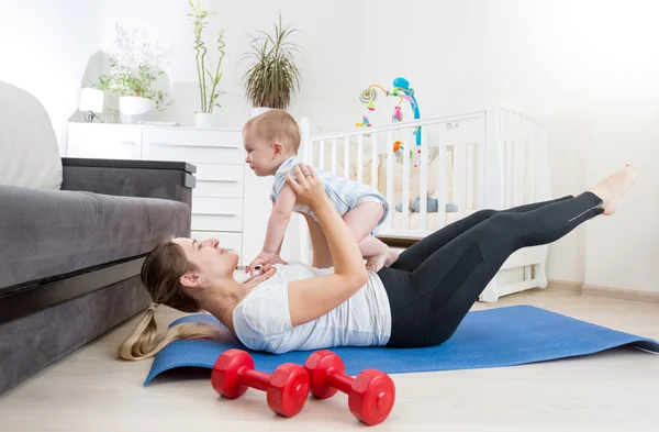 Beautiful mother with baby doing physical exercises on fitness m
