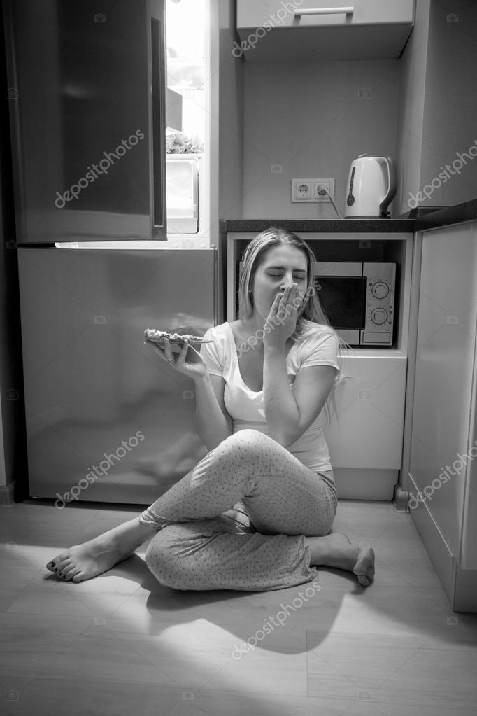 Zwart wit foto van slaperig vrouw zitten volgende open refriger ...