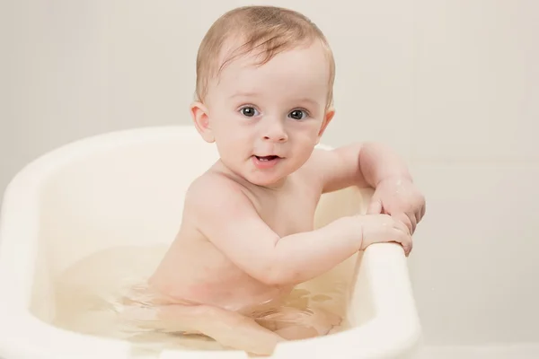 Toned portrait of lovely baby taking bath with foam